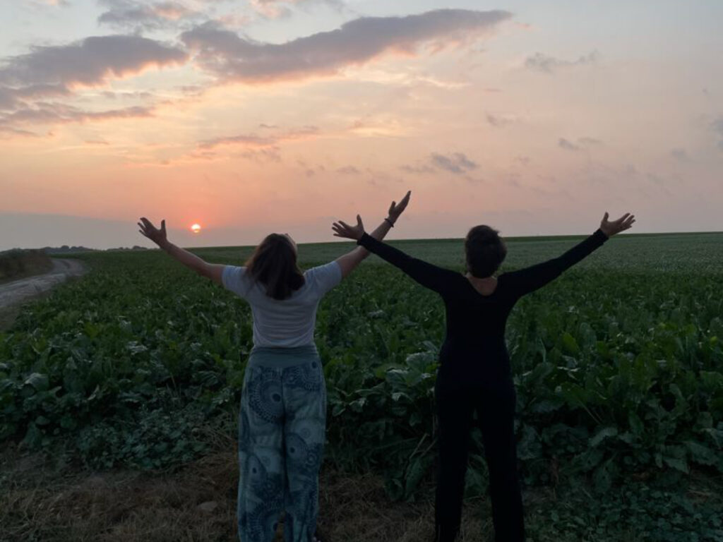 Deux femmes de dos ouvrant les bras au ciel lors d'un coucher de soleil