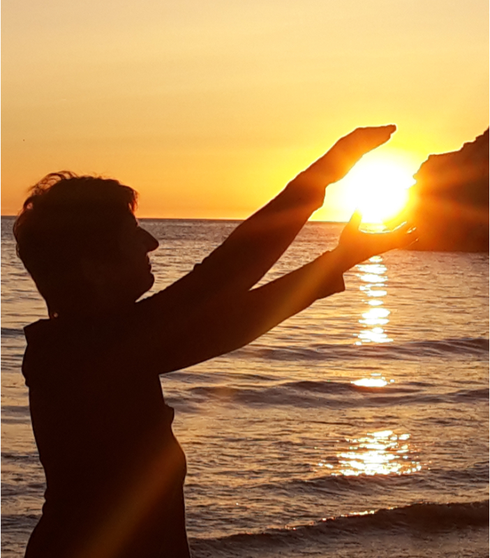 Femme tenant le soleil entre ses main au coucher de soleil en bord de mer